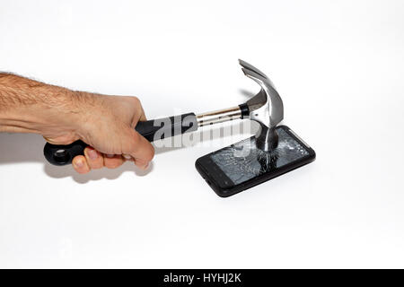 Ein Hammer fällt eine Telefon, erschütternd sein Bildschirm Stockfoto