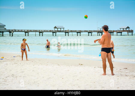 Vater und Sohn werfen Ball am weißen Sandstrand von Clearwater Beach, FL entlang der Küste mit Pier 60 im Hintergrund milde Blauwasser Surf-und swimme Stockfoto