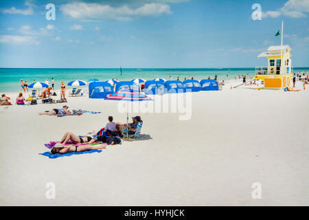 Ansicht von Menschen genießen die weißen Sand und türkisfarbenem Wasser von Clearwater Beach, FL, mit Nummer 5 Rettungsschwimmer-Turm und blau und weiß-Cananas und umbr Stockfoto