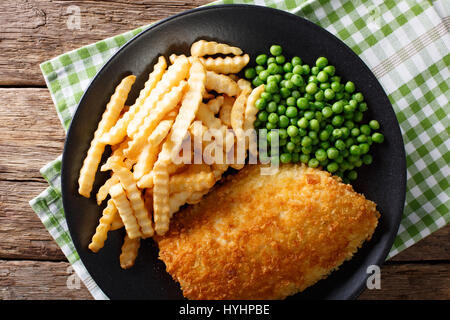 Fish And Chips mit grünen Erbsen Nahaufnahme auf einer Platte auf einem Tisch. horizontale Ansicht von oben Stockfoto