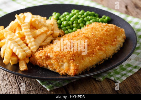 Fish And Chips mit grünen Erbsen Nahaufnahme auf einer Platte auf einem Tisch. horizontale Stockfoto