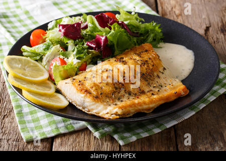 Gegrillter Saibling-Filet mit gemischtem Salat und Sauce auf einer Platte Nahaufnahme. horizontale Stockfoto