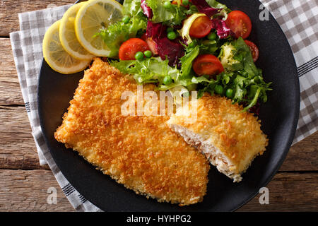 Paniertes Fischfilet in Panade und frischen Gemüsesalat Nahaufnahme auf einer Platte. horizontale Ansicht von oben Stockfoto