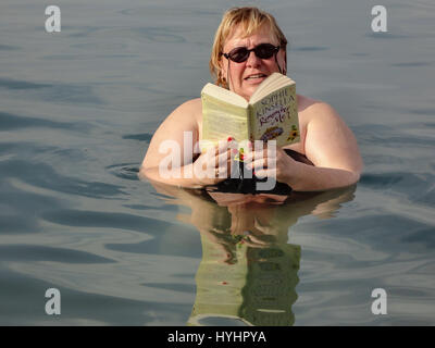 Eine Frau in Te Toten Meer schweben ein Taschenbuch zu lesen. Stockfoto