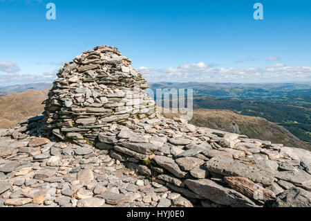 Gipfel Cairn auf der Oberseite Coniston Greis im englischen Lake District.  Die Aussicht auf die umliegende Landschaft umfasst Lake Windermere in der dista Stockfoto