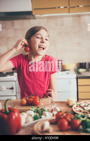 Niedliche kleine Mädchen herumalbern mit Tomaten in der Küche Stockfoto