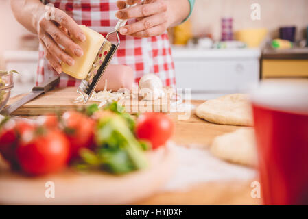 Frau Gitter Käse für Pizza In der Küche Stockfoto