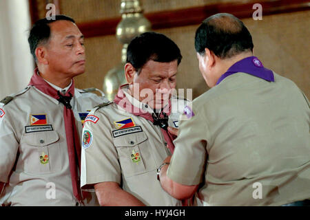 Manila, Philippinen. 4. April 2017. Philippinische Präsident Rodrigo Duterte erhält die Carabao Folie und Halstuch von Pfadfinder von den Philippinen nationaler Präsident Wendel Avisado und BSP Hauptkommissar National Cedrick Zug links, blickt auf in Rizal Halle im Malacanang Palace 3. April 2017 in Manila, Philippinen. Das Ereignis feierte Baden Powell Tag, Gründer der Pfadfinder-Organisation. Bildnachweis: Planetpix/Alamy Live-Nachrichten Stockfoto