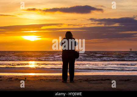 Southport, Merseyside, England. 4. April 2017. Großbritannien Wetter.  Farbenfrohen Sonnenuntergang über die irische See als Menschen an der Küste genießen Sie die Strahlen der untergehenden Sonne am Horizont von der Mündung des Mersey.  Kredite; MediaWorldImages/AlamyLiveNews Stockfoto