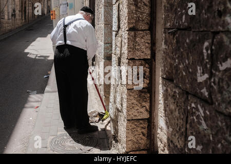 Jerusalem, Israel. 5. April 2017. Ein Mann fegt durch eine Tür im Stadtteil Mea Shearim in Vorbereitung für Pessach, heuer Anfang Sonnenuntergang, 10. April 2017 gefeiert werden. Die rituelle reichen Urlaub schreibt vor, dass die Juden alle gesäuerten Produkte, "Chametz", aus ihren Küchen und Häusern zu entfernen. Mea Shearim ist eines der ältesten jüdischen Viertel in Jerusalem und völlig von ultra-orthodoxen Haredi Juden bevölkert. Bildnachweis: Nir Alon/Alamy Live-Nachrichten Stockfoto