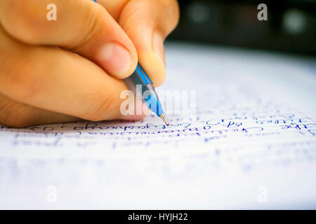 Menschliche Hand mit Stift auf weißem Papier mit Tastatur in den Boden zurück, isoliert, Tiefenschärfe, geringe Schärfentiefe, Konzept der Business & educa Stockfoto