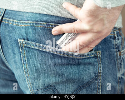 seine Hand Dollar in Jeans Tasche stecken oder aus der Tasche nehmen Stockfoto