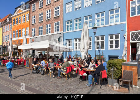 Die historischen Hafenrestaurants in Nyhavn, Kopenhagen, Dänemark, locken viele Kopenhagener und Touristen an einem sonnigen Frühlingstag Anfang April Stockfoto