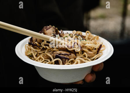 Mittelteil der Frau hält Street Food mit Nudeln und Fleisch. Vordergrund im Fokus Stockfoto