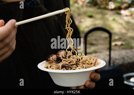 Mittelteil der Frau hält Street Food mit Nudeln, Fleisch und Gemüse. Vordergrund im Fokus Stockfoto