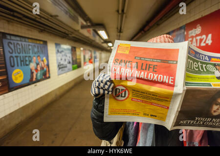 Ein pendler liest eine Kopie einer Zeitung, während in der U-Bahn mit einem New York Abt. der Gesundheit Werbung Menschen drängen Naloxon ein Antidot für eine Überdosierung mit Opioiden, am Samstag, dem 1. April 2017, durchführen. Wie ein opioid Epidemie breitet sich über das Land, Gesundheit Abteilungen fordern die Durchführung von Naloxon bei der oft Chance, dass sie eine Überdosis Süchtiger begegnen. (© Richard B. Levine) Stockfoto