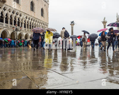 Touristen mit Sonnenschirmen auf einem nassen und regnerischen Tag in Markusplatz entfernt (Piazzetta di San Paulo), Venedig, Italien Stockfoto