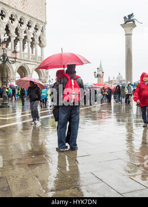 Touristen mit Sonnenschirmen auf einem nassen und regnerischen Tag in Markusplatz entfernt (Piazzetta di San Paulo), Venedig, Italien Stockfoto