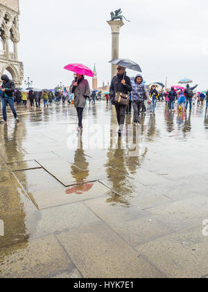 Touristen mit Sonnenschirmen auf einem nassen und regnerischen Tag in Markusplatz entfernt (Piazzetta di San Paulo), Venedig, Italien Stockfoto