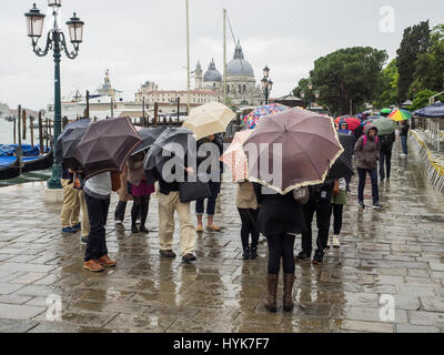 Touristen mit Sonnenschirmen auf einem nassen und regnerischen Tag in Markusplatz entfernt (Piazzetta di San Paulo), Venedig, Italien Stockfoto