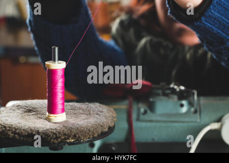 Detail der Näherin rosa Faden in eine professionelle Nähmaschine setzen Stockfoto