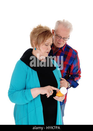 Ein senior Frau zeigt ihr Ehemann seine Medikamente, beide stehend Closeup für weißen Hintergrund isoliert. Stockfoto