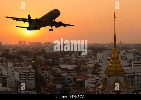 Silhouette Passagierflugzeug fliegen über die Stadt bei Sonnenuntergang Stockfoto