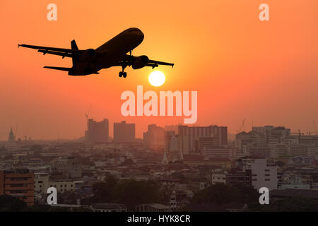 Silhouette Passagierflugzeug fliegen über die Stadt bei Sonnenuntergang Stockfoto