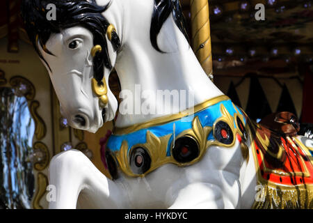 Ein Karussell in Paris. Nahaufnahme von einem schönen weißen Pferd mit schwarzer Mähne und bunten Accessoires warten auf einen Fahrer an einer merry Go round in Frankreich. Stockfoto