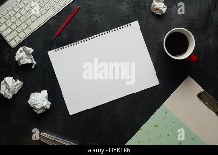 Holz schwarz Schreibtisch Bürotisch mit Notebook, Tastatur und Tasse Kaffee. Leere Notizbuchseite für die Eingabe der Text in der Mitte. Ansicht von oben Stockfoto