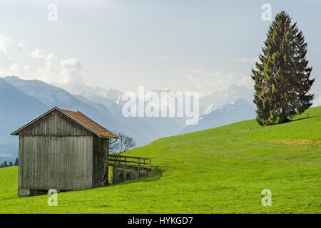 Anzeigen von hölzernen Scheune auf schneebedeckte Berge im Frühling Stockfoto