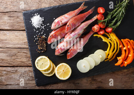 Roher Fisch Rotbarbe mit pflanzlichen Zutaten und Gewürzen close-up auf dem Brett Küche. horizontale Ansicht von oben Stockfoto