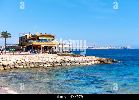 Punta Prima, Spanien - 28. März 2017: Touristen sitzen in einem Café direkt am Meer. Punta Prima ist ein beliebter Touristenort. Provinz Alicante. Südspanien Stockfoto