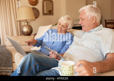 Lächelnden Senioren Surfen im Internet auf ihrem Sofa zu Hause Stockfoto