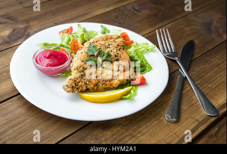 serviert hausgemachte panierte Schnitzel mit Salat und Berry Sauce auf alten Holztisch Stockfoto