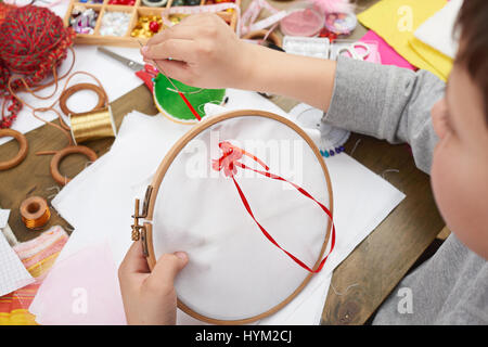 Junge auf Reifen, Hand Closeup und rotes Band auf weißen Textilien bestickt erfährt, Nähen, job, Ausbildung, Handarbeit und Kunsthandwerk-Konzept Stockfoto