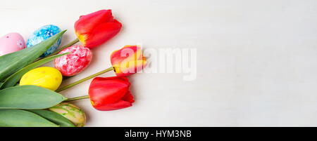 Rote Tulpen und bemalte Ostereier auf Holztisch Stockfoto