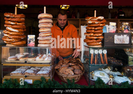 Aussteller in seinem Stand von typischen Produkten an den traditionellen Weihnachtsmärkten von Bozen in Italien. Stockfoto