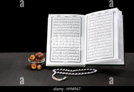 Offenes Buch der Koran mit Rosenkranz und Termine über schwarzen Hintergrund Stockfoto