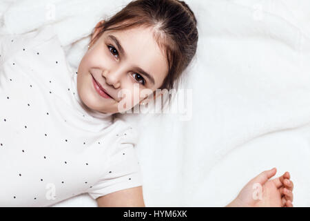 Draufsicht auf niedliche Brünette Mädchen auf dem Bett liegend. Stockfoto