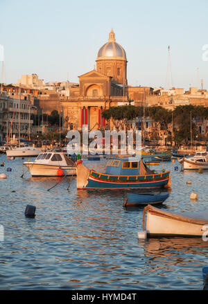 Die Ansicht der Kirche St. Joseph am Ufer und einer traditionellen maltesischen Boote (Luzzu) in der Bucht von Kalkara zwischen Birgu und Kalkara Halbinsel, Malta. Stockfoto