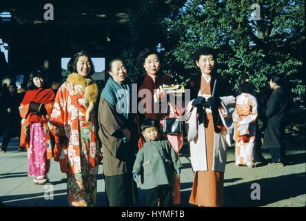 Eine japanische Familie posiert mit den Frauen tragen traditionelle bunte Gewänder und Kimonos, für ein Bild vor einem Schrein, 1952. Stockfoto