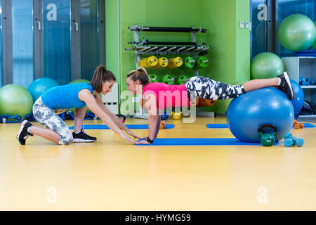 Trainer helfen Frau im Sport auf ball Stockfoto