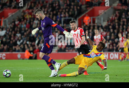 Southampton Torwart Fraser Forster (links) nimmt den Ball Weg von Crystal Palace Wilfried Zaha während des Premier-League-Spiels an Str. Marys Stadium, Southampton. Stockfoto