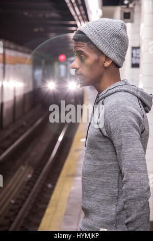 Eine junge, schwarze Hipster wartet auf einer New Yorker u-Bahn. Gedreht im Herbst 2016. Stockfoto