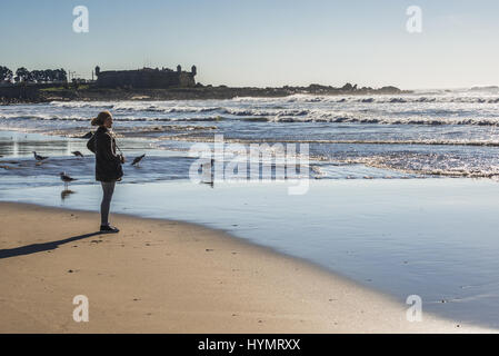 Frau auf den Strand von Nevogilde Zivilgemeinde der Stadt Porto, Portugal. Festung von Sao Francisco Queijo (so genannte Burg von Käse) auf Hintergrund Stockfoto