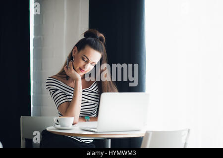 Auf der Suche nach Inspiration. Junge schöne nachdenkliche Frau einige Notizen machen und sie sitzend in einem Stuhl an ihrem Arbeitsplatz oder einem Café anzusehen Stockfoto