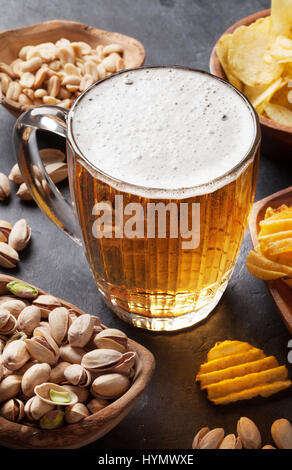 Lager-Bierkrug und Snacks am Steintisch. Muttern, chips Stockfoto