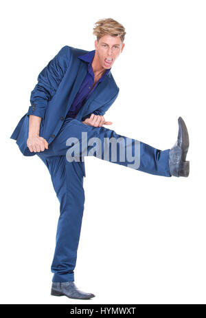 In voller Länge Portrait eines jungen Mannes kicking Bein bis auf weißen Hintergrund isoliert Stockfoto