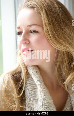 Porträt einer schönen Frau starrte außerhalb durch Fenster schließen Stockfoto